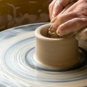 person making clay pot on white round plate