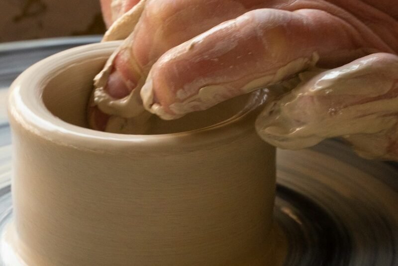 person making clay pot on white round plate